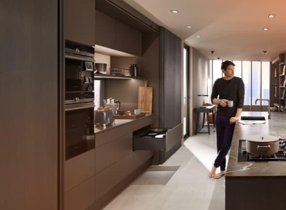 A man in a stylish kitchen, an open drawer showing LEGRABOX.