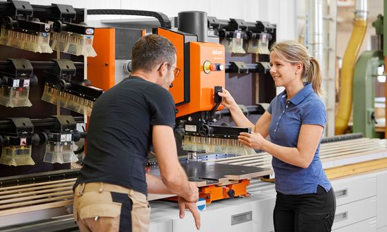 Odbornice společnosti Blum ukazuje truhláři, jak vyměnit vrtací hlavu na vrtacím a lisovacím stroji MINIPRESS top.