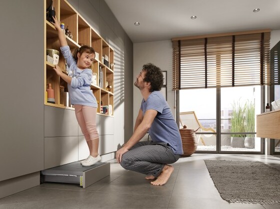 Дівчинка стоїть на висунутій сходинці SPACE STEP - шухляді для цоколю, що створює у ній корисний простір